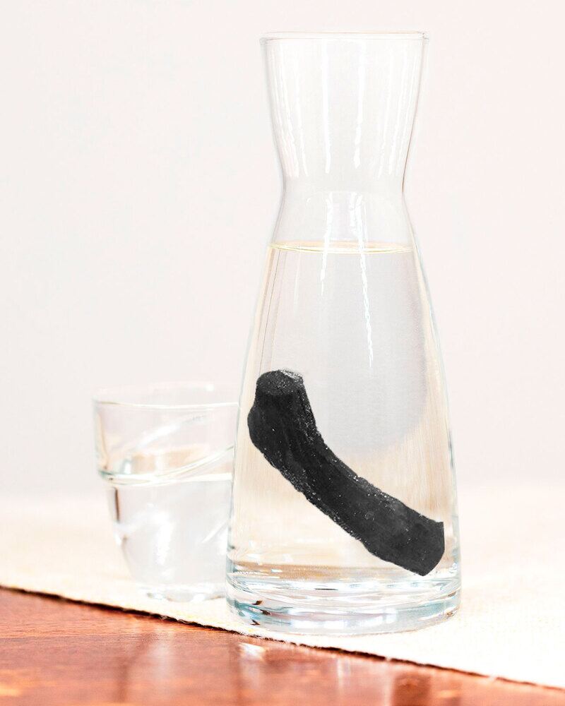 Un bâton de binchotan dans une carafe d'eau claire